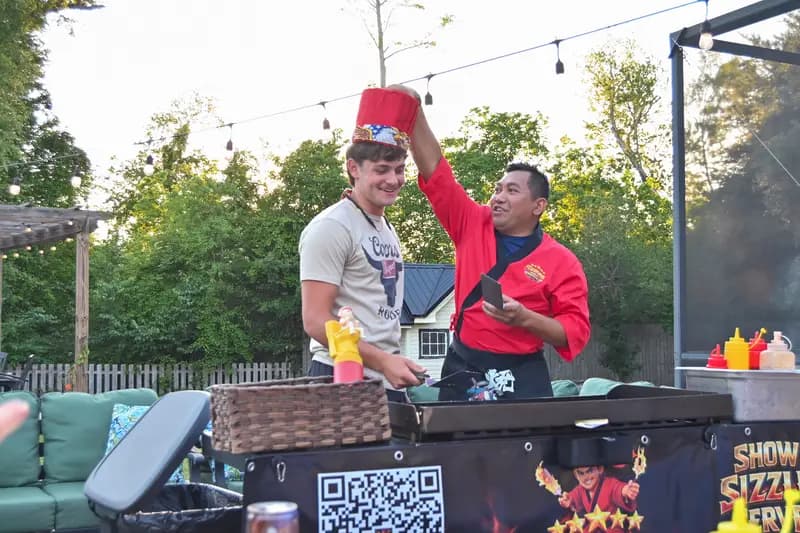 Hibachi chef putting hat on guest